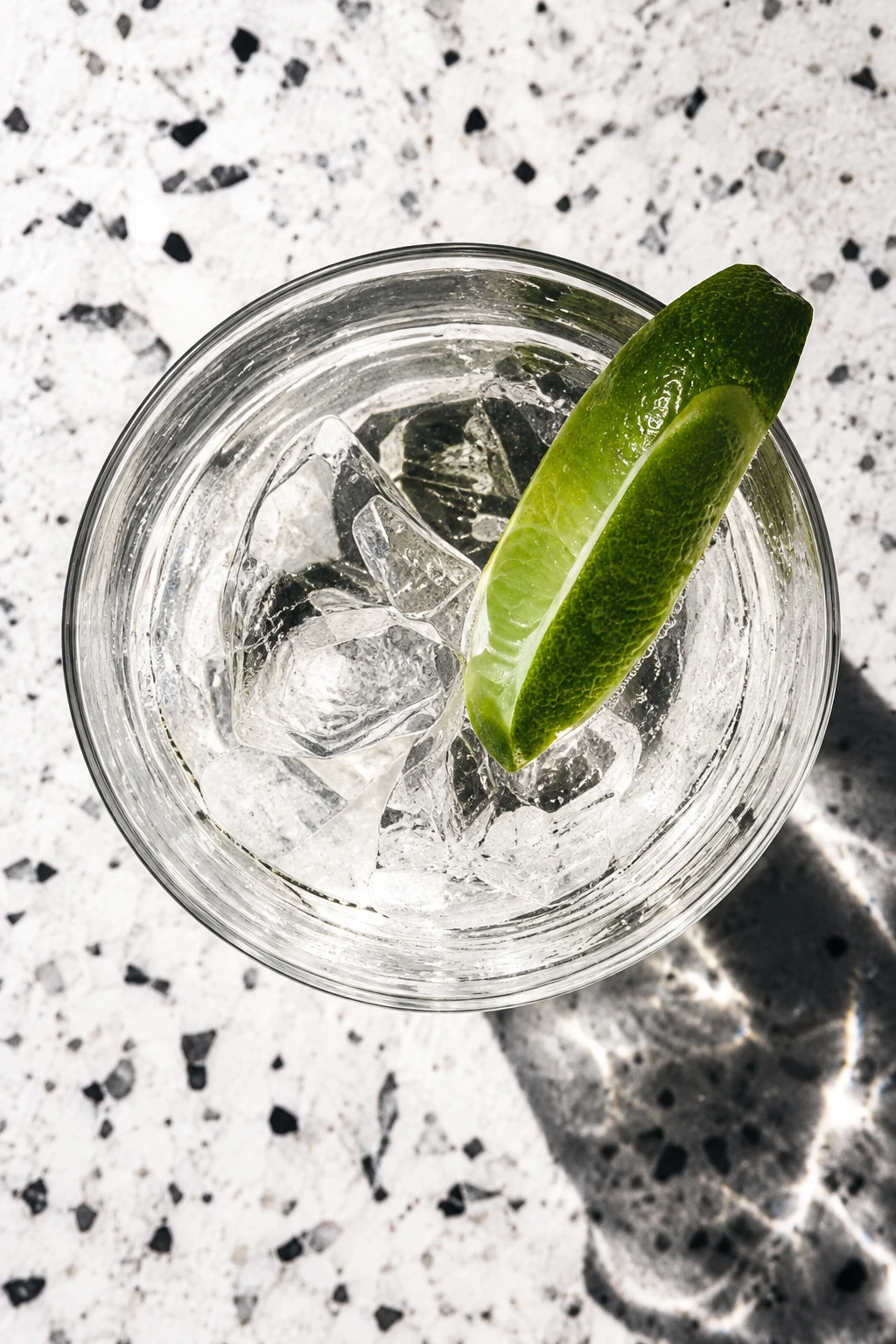 Overhead lime cocktail on a speckled stone surface